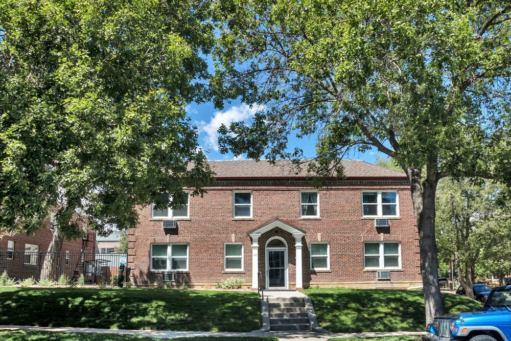 a large brick house with trees in front of it