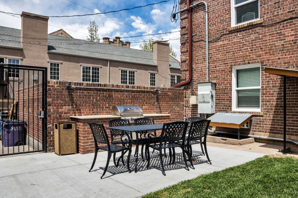 a patio with a table and chairs and a grill