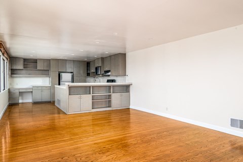 an empty living room and kitchen with wood flooring