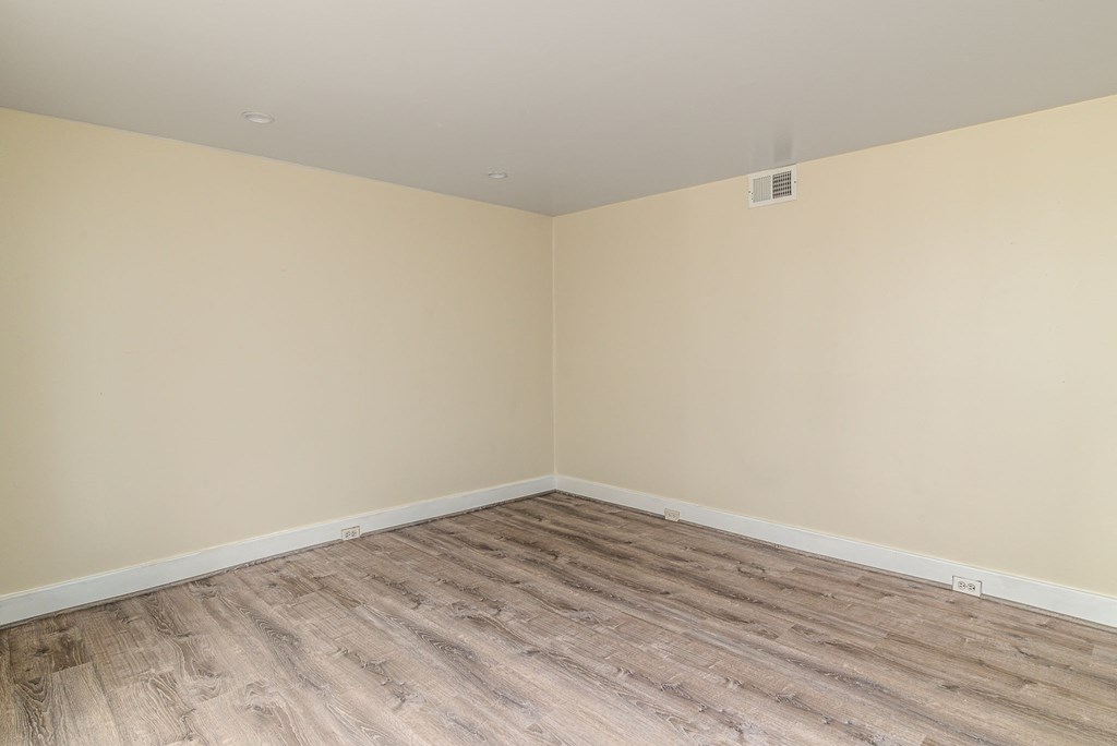 an empty room with wood flooring and beige walls