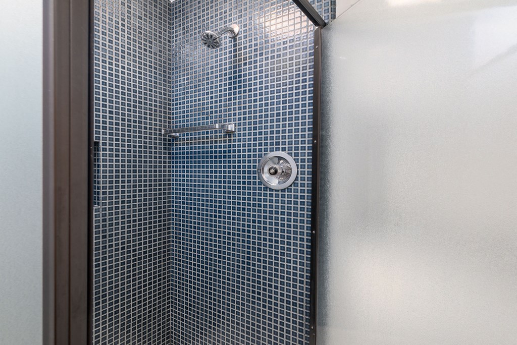 a blue tiled shower in a white bathroom
