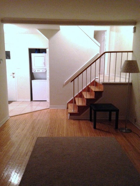 A hallway with a staircase and a table with a lamp.