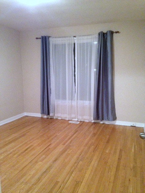 A room with a window covered by a grey curtain.
