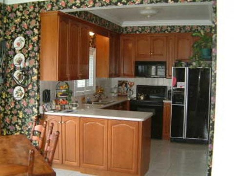A kitchen with wooden cabinets and a black refrigerator.