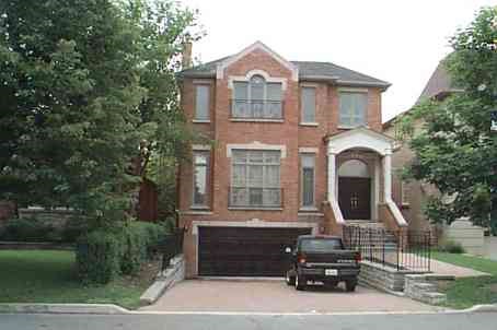 A black car is parked in front of a red brick house.