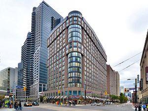 A large building with many windows is in the middle of a city street.