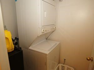 A small white refrigerator sits in a corner of a small kitchen.