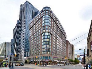 A large building with many windows is in the middle of a city street.
