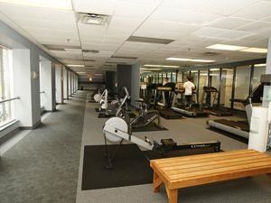 A gym with a variety of equipment including treadmills, weights, and a bench.