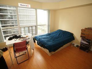 A bedroom with a bed, desk, and chair.