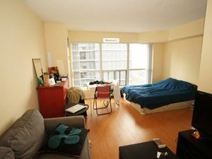 A living room with a grey couch and a blue bed.