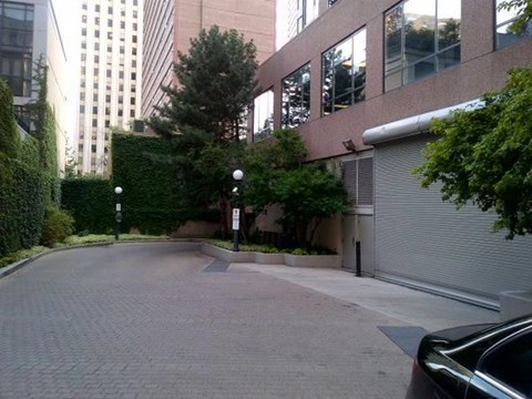 A black car is parked on a brick road.
