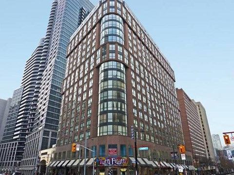 A tall building with a curved glass facade stands next to a shorter building with a brick facade.