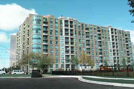 A large building with many windows is surrounded by a black fence.