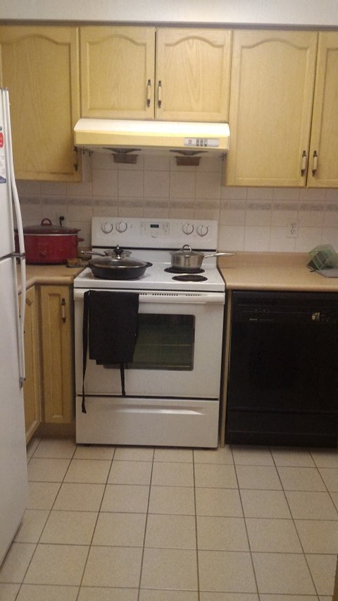 A kitchen with a white stove and black oven.