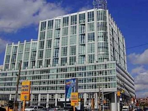 A large glass building with a sign that says "PARK HERE" on the side.