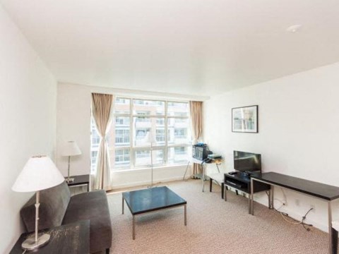 A living room with a couch, a chair, a coffee table, a television, and a window with curtains.