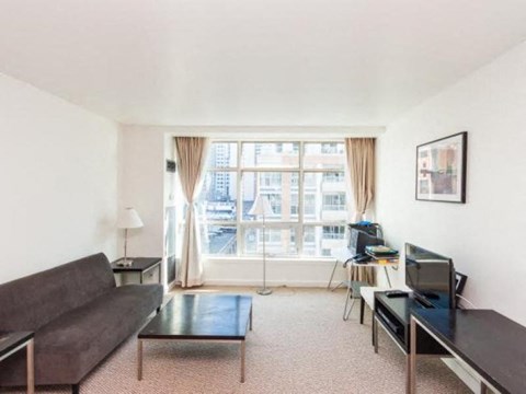 A living room with a couch, a chair, a coffee table, and a television.