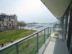 A balcony overlooks a grassy area and a body of water with boats.