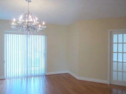 A room with a chandelier and a window with blinds.