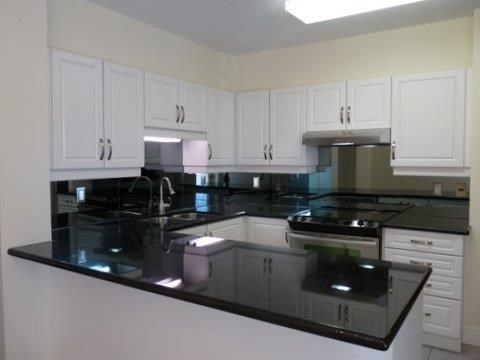 a kitchen with white cabinets and black counter tops