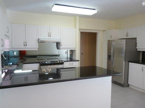 A kitchen with white cabinets and a black countertop.
