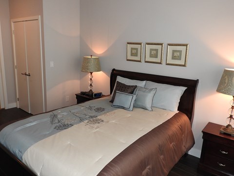 A bedroom with a large bed and two lamps.