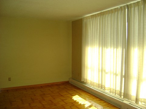 A room with a window covered by white curtains.