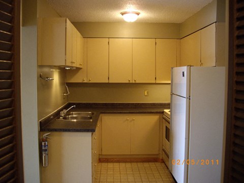 A kitchen with a white refrigerator and cabinets.