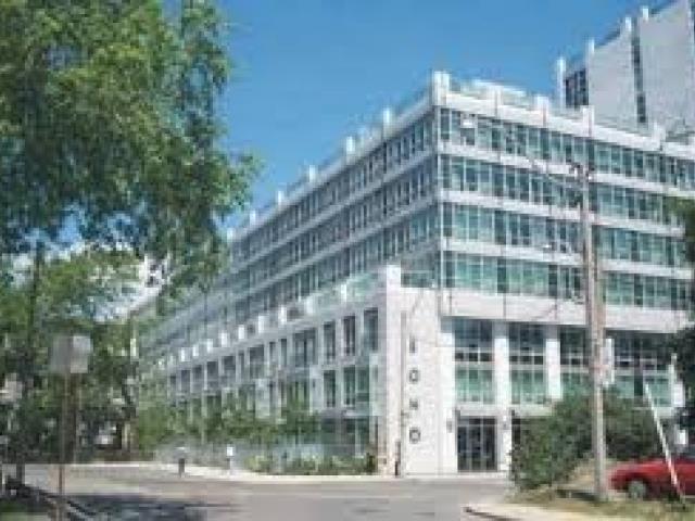 A large glass building with trees in front.