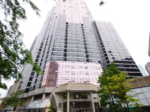 A tall building with a glass facade stands in front of a smaller building.
