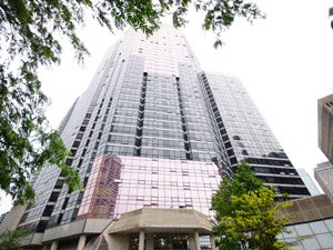 A tall building with a glass facade stands between two trees.