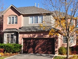 A house with a brown garage door and a tree in front.