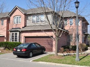 A black car is parked in front of a red brick house.