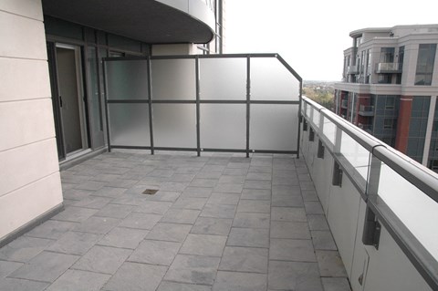 A balcony with a glass railing and tiled floor.
