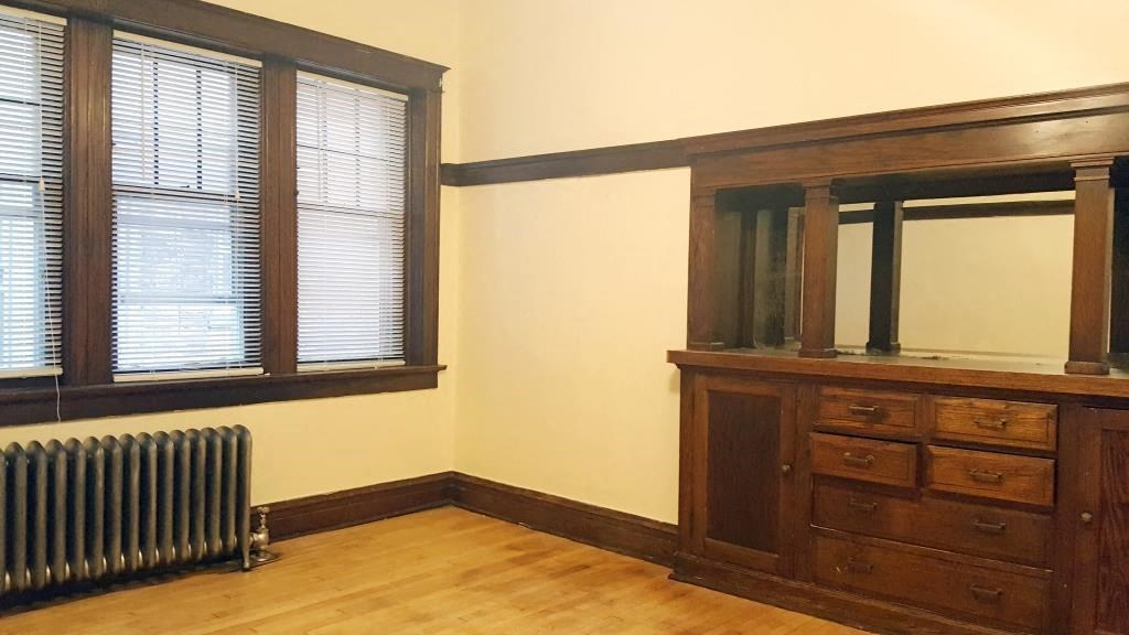 an empty room with a dresser and a radiator