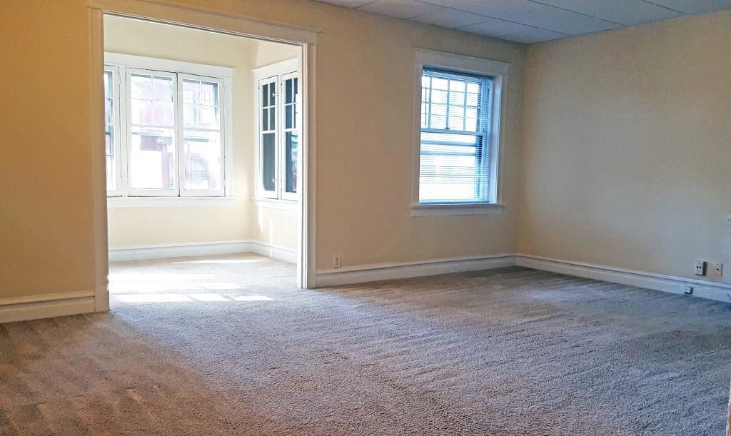 an empty living room with a door and a window