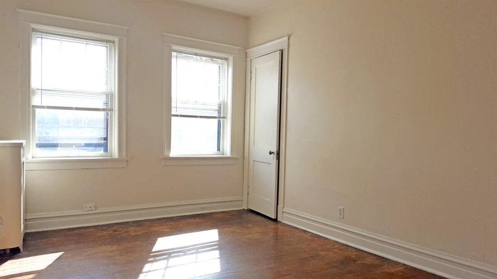 an empty room with a door and two windows