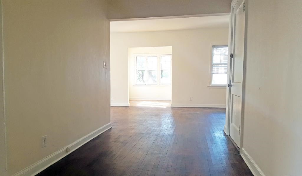 an empty living room with white walls and wood floors