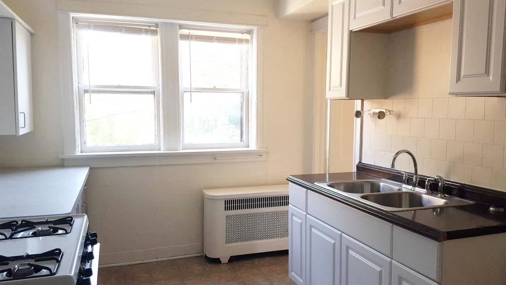 a kitchen with a sink and a stove and two windows