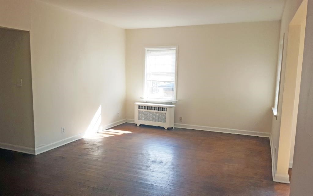 an empty room with a window and wooden floors