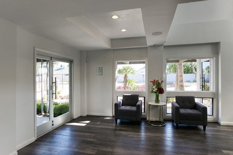 a living room with two chairs and a table and windows