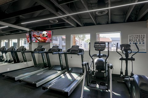 a gym with cardio equipment and windows in a building