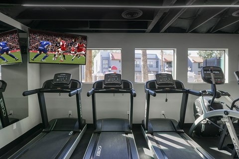a gym with cardio machines and televisions on the wall