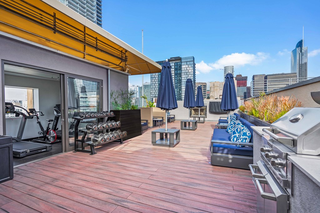 a deck with a grill and a city skyline in the background