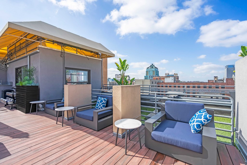 a rooftop patio with couches and tables and a city in the background