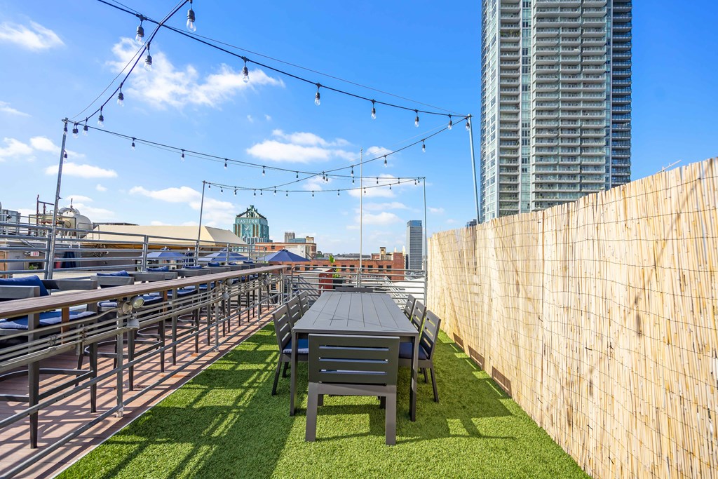 a rooftop patio with a table and chairs and a view of the city
