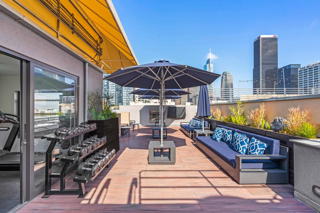 a rooftop patio with tables and chairs and an umbrella