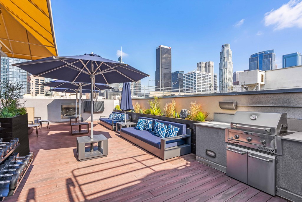 a rooftop deck with a grill and a city skyline in the background
