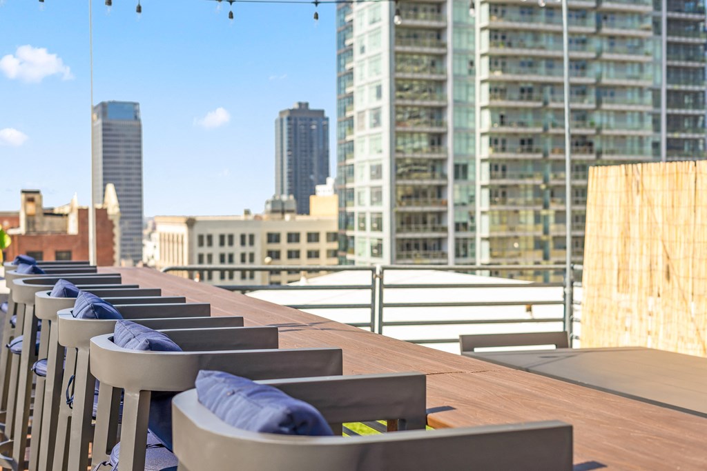 a row of chairs and a table on a balcony overlooking a city